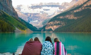 A family of four sits by Lake Louise in Banff, Alberta