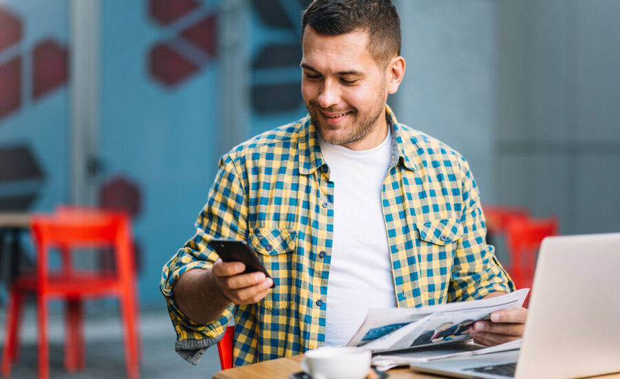Man logging into his online broker account after reading the newspaper and MoneySense's "Best online brokers in Canada"