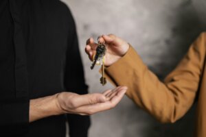 A person is seen handing keys to a house to another person.