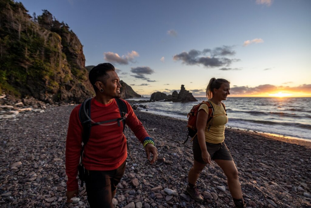 A man and woman hiking on a rocky beach