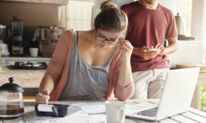 A couple is seen looking at paper work on a table.