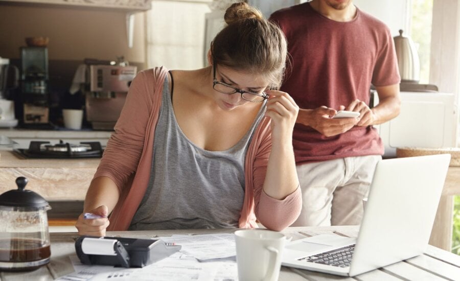 A couple is seen looking at paper work on a table.