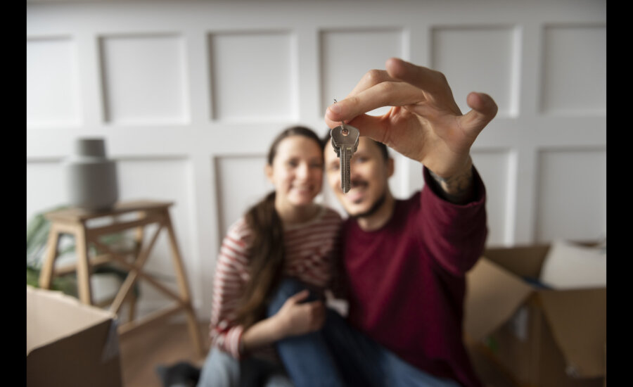 Couple holding up a key to their new home.