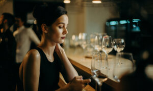 A Canadian single woman at work, looking at her investments on her phone.
