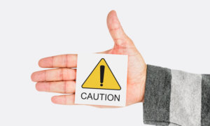 Hand holding a caution sign, symbolizing the Bank of Canada's caution messages with this week's rate hold.