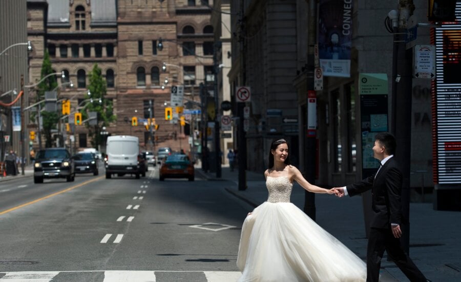 A couple poses for photographs in their wedding outfits during photo shoot in the middle of a street in Toronto on Friday, June 5, 2020.