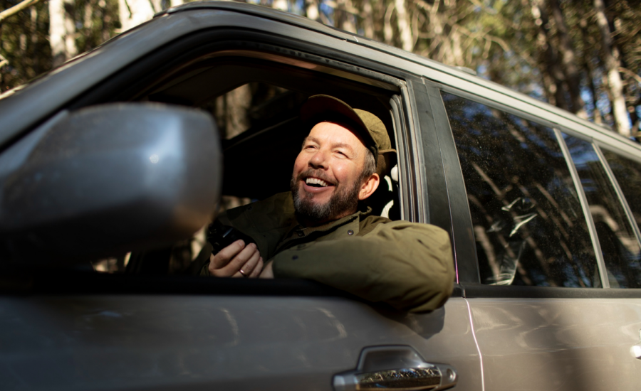 A smiling man driving a pickup truck