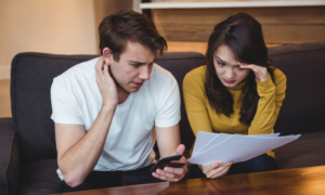 A young man and woman look worried while reviewing bills