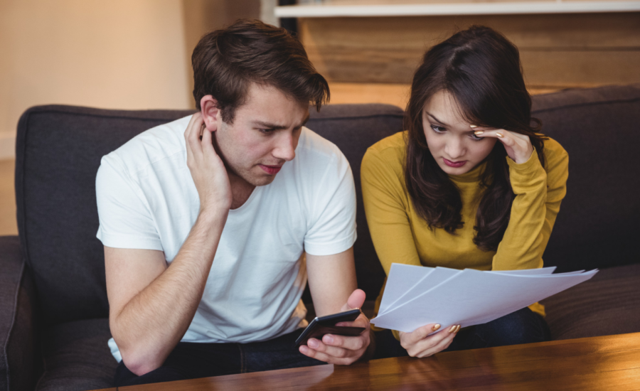 A young man and woman look worried while reviewing bills