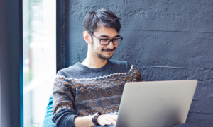 A smiling young man using a laptop
