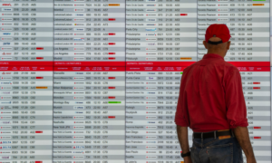 A man stands in front of a flight information screen at an airport