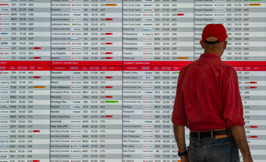 A man stands in front of a flight information screen at an airport