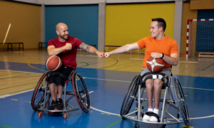Two smiling men bump fists while playing wheelchair basketball