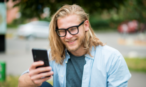 Smiling young man checks his crypto portfolio on his phone