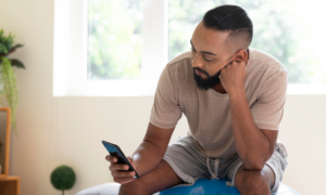 A young man reads on his phone at home