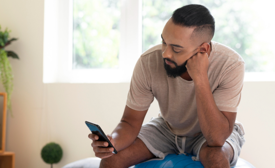 A young man reads on his phone at home