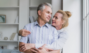 A man and woman hug in their living room