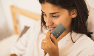 A woman holding a credit card while she shops online