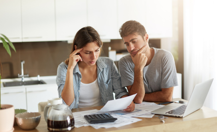 A woman and man look at unpaid bills in their kitchen