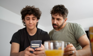 A dad and teenage son look at RESP info on a phone.