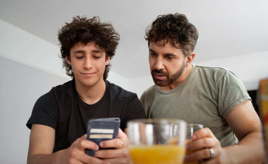 A dad and teenage son look at RESP info on a phone.