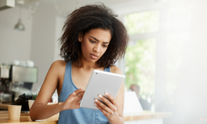 A worried young woman checks her tablet