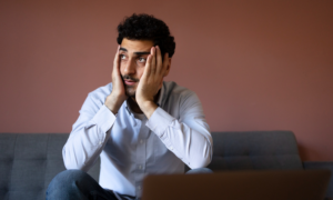 A worried-looking young man sits on a sofa