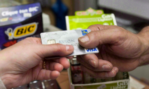 A customer's hand passing a credit cart to a clerk at a store