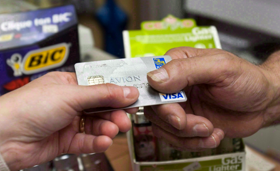 A customer's hand passing a credit cart to a clerk at a store