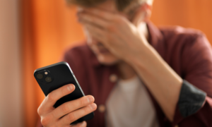 A man looks worried as he checks a credit bill on his phone