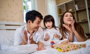 A young mom and dad sing with their toddler daughter