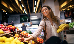 A smiling woman buying fruit at the supermarket
