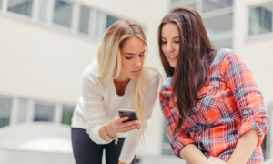 Two young women look at a phone