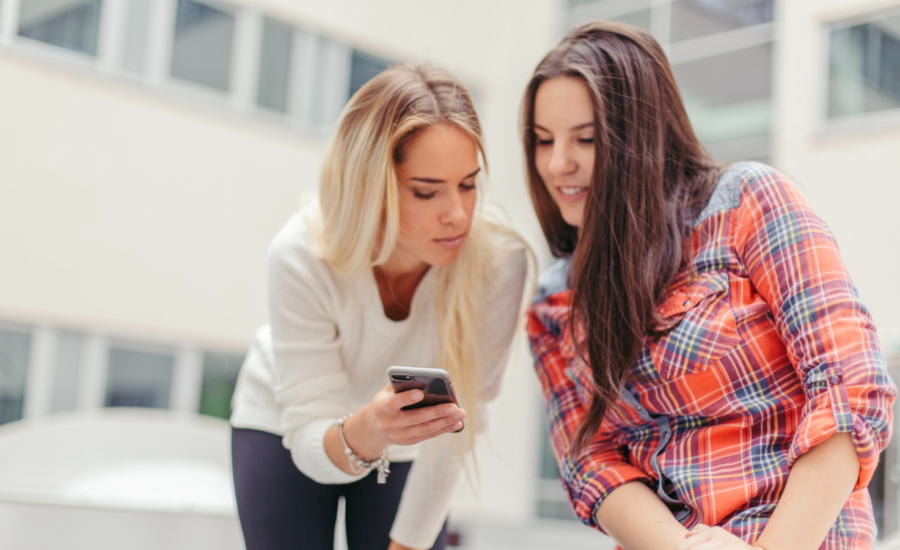 Two young women look at a phone