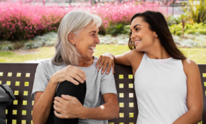 A senior-aged woman and her daughter chat on a park bench
