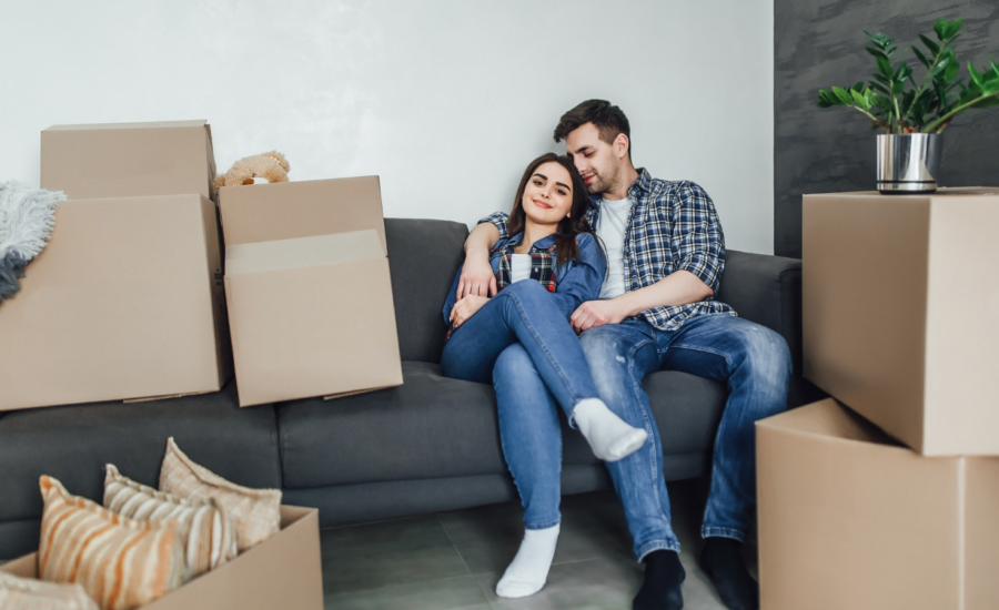 A young woman and man on a sofa with moving boxes