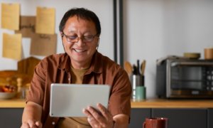 A smiling man uses an iPad in his kitchen
